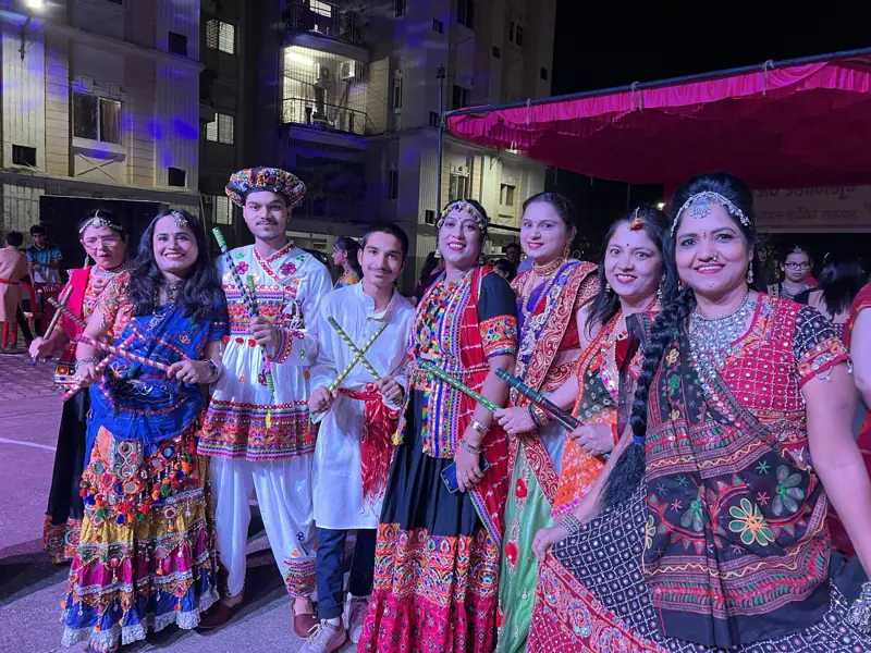 Residents in traditional garba attire holding dandiya sticks
